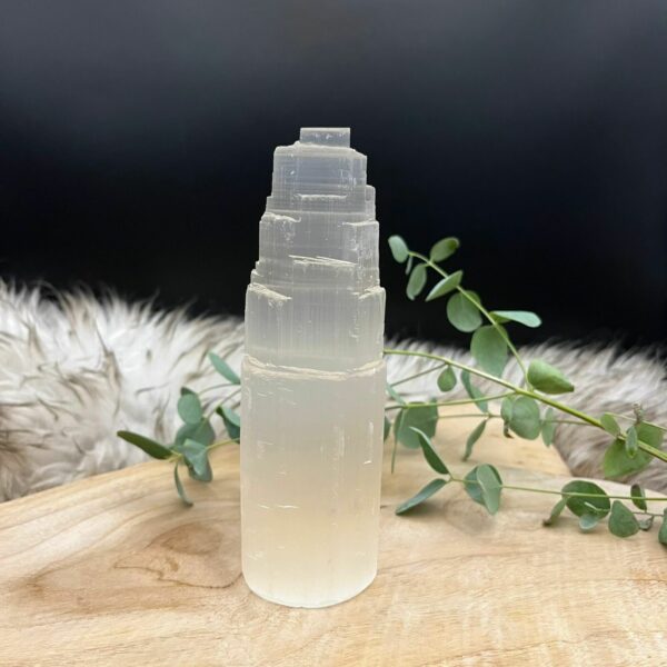 Seleniet toren op een houten tafel met kaarsen en edelstenen, Glanzende seleniet toren in een spirituele meditatiehoek, Seleniet toren naast andere mineralen voor energiezuivering, Seleniet toren, Seleniet toren 15 cm